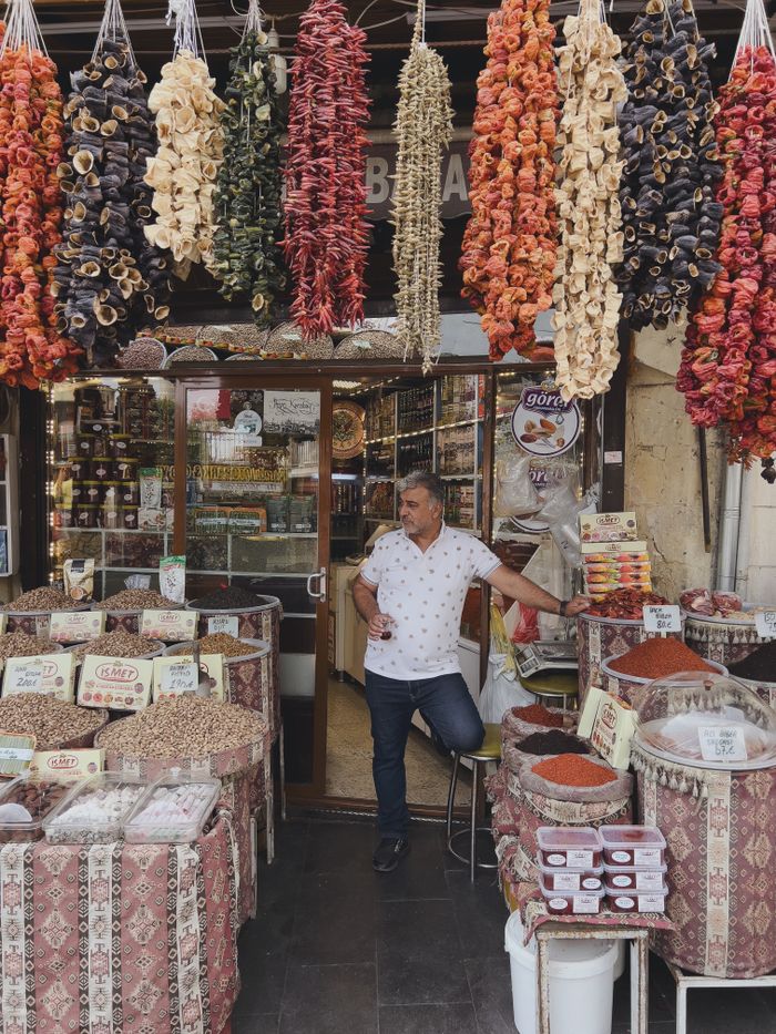 Man at a vibrant market stall selling various spices and dried herbs.