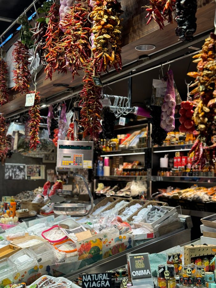 Colorful market stall in Barcelona, Spain displaying a variety of spices and goods.