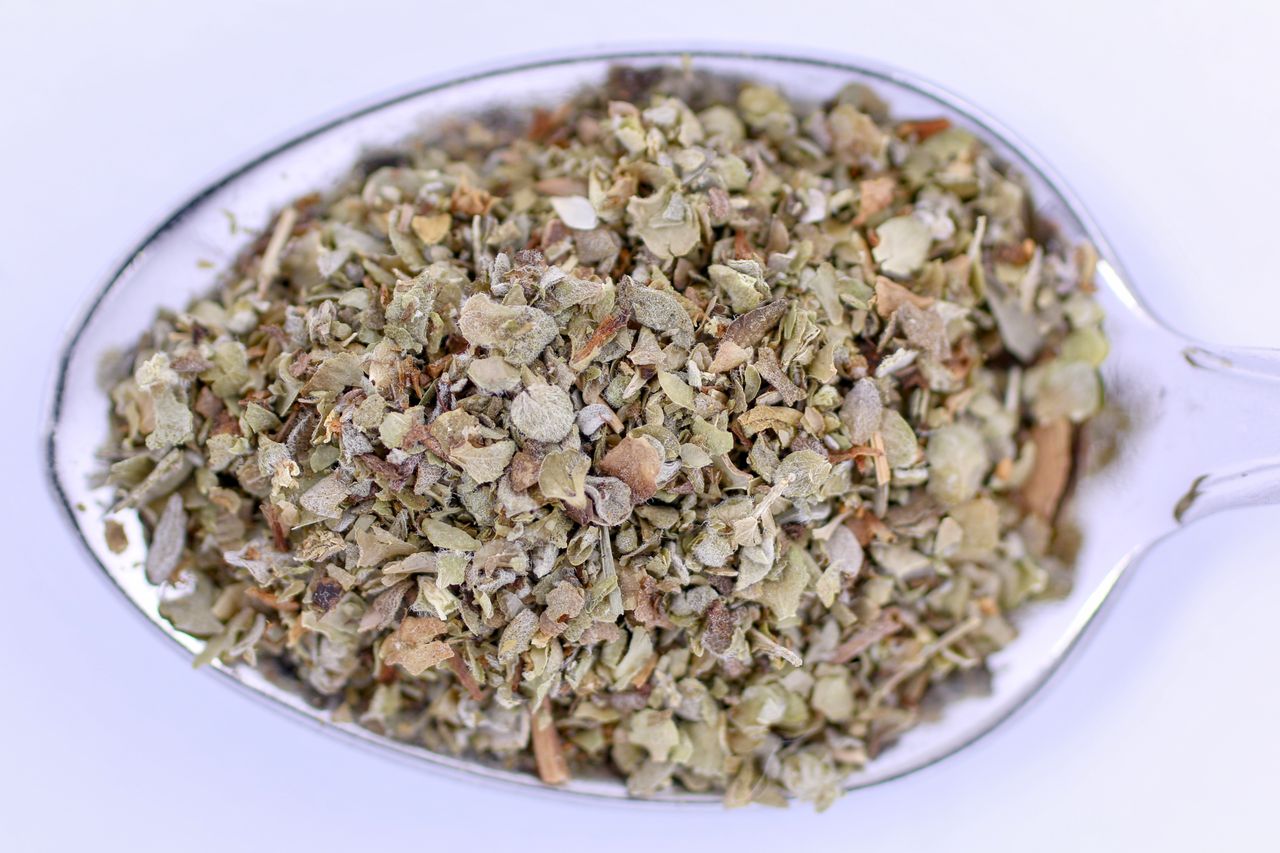 Detailed image of marjoram seasoning in a metal teaspoon, perfect for culinary uses.